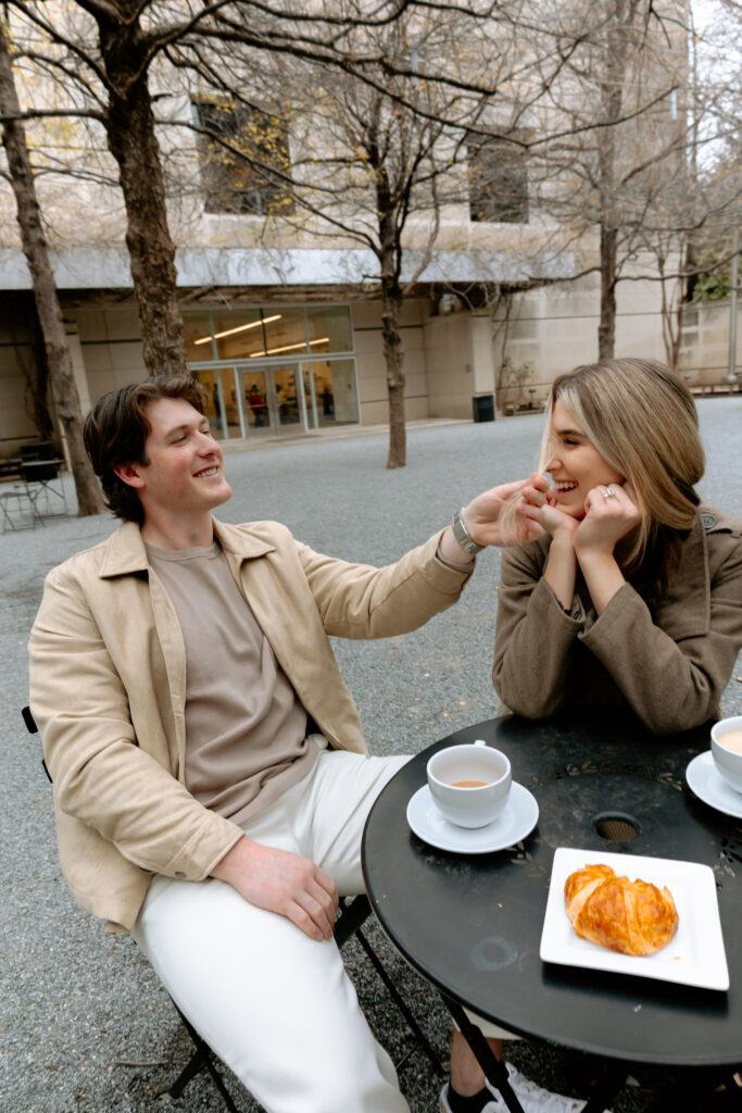 Photograph of engaged couple sitting with the man playing with the woman's hair