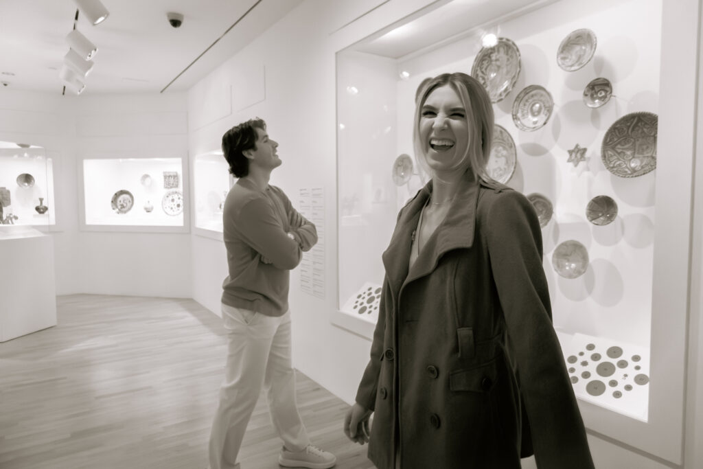 A woman laughing at the camera while her fiancé is in the background