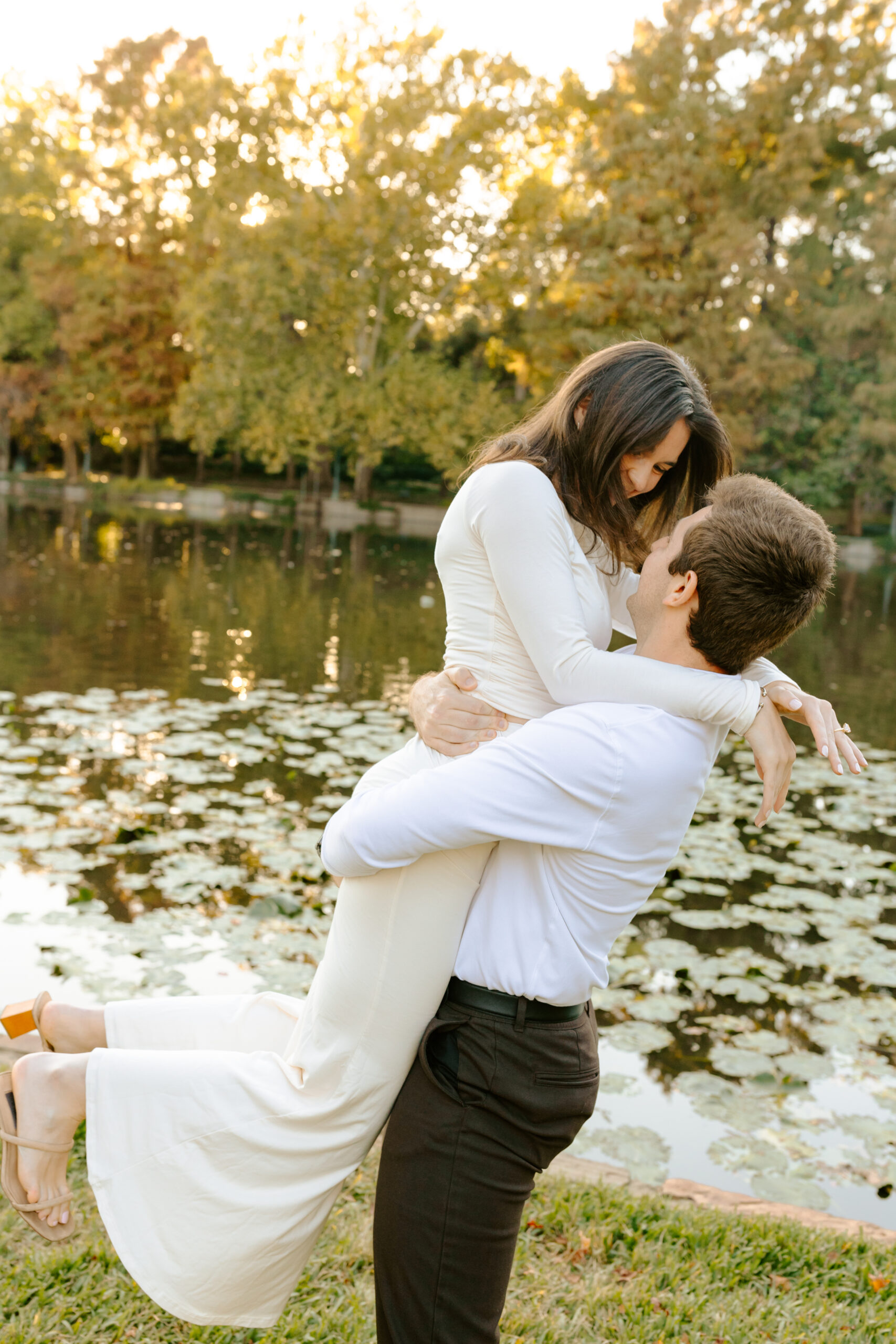 Guy holding and spinning his fiancé in front of the lake in Dallas