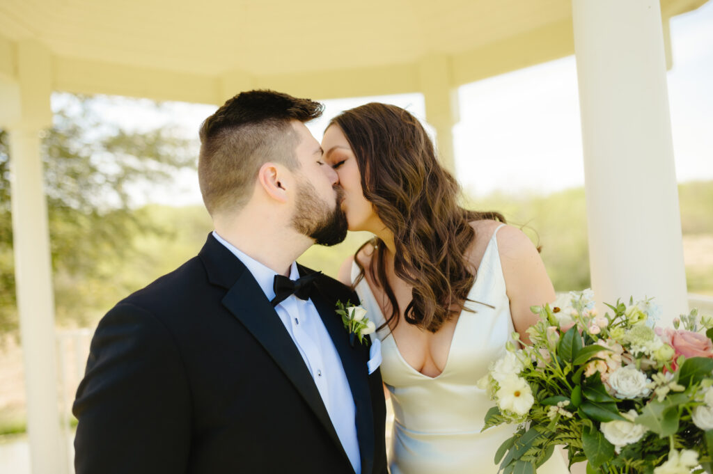 Bride and groom kissing close up photo under a gazebo