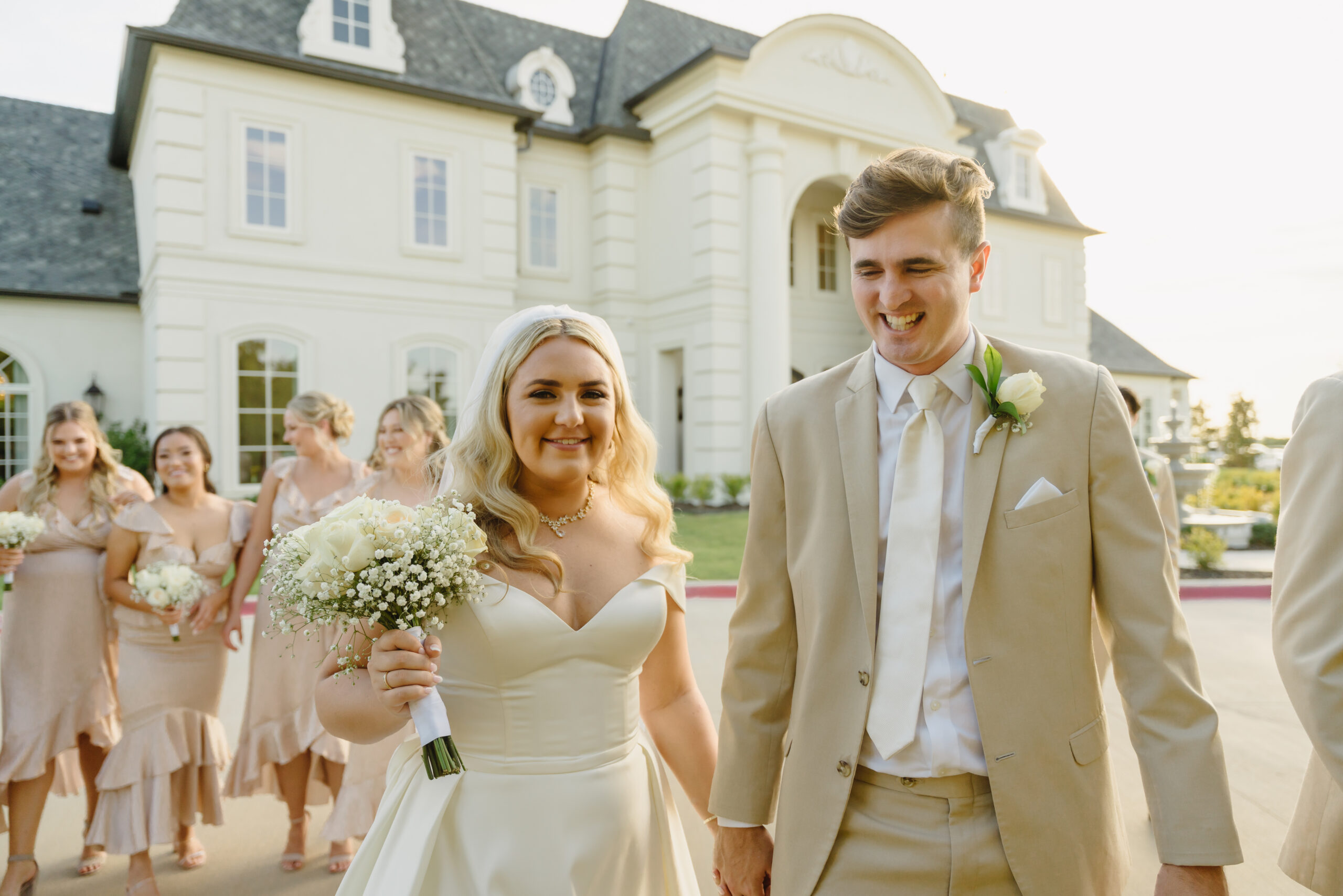 Bride and groom walking outside of their venue with their wedding party behind them
