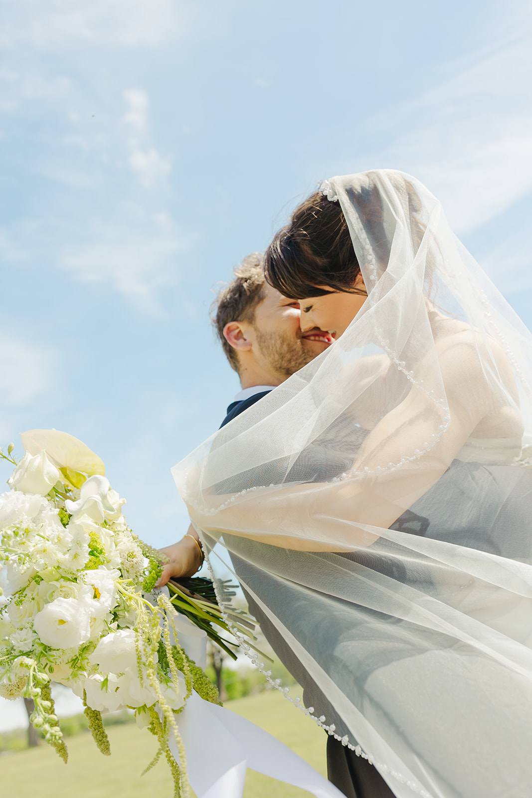 Bride and groom hugging veil photo outside in Dallas